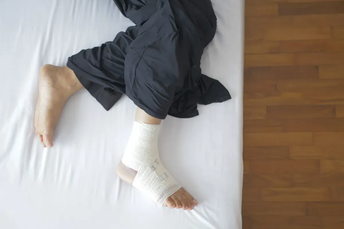 Un pie vendado apoyado sobre una cama