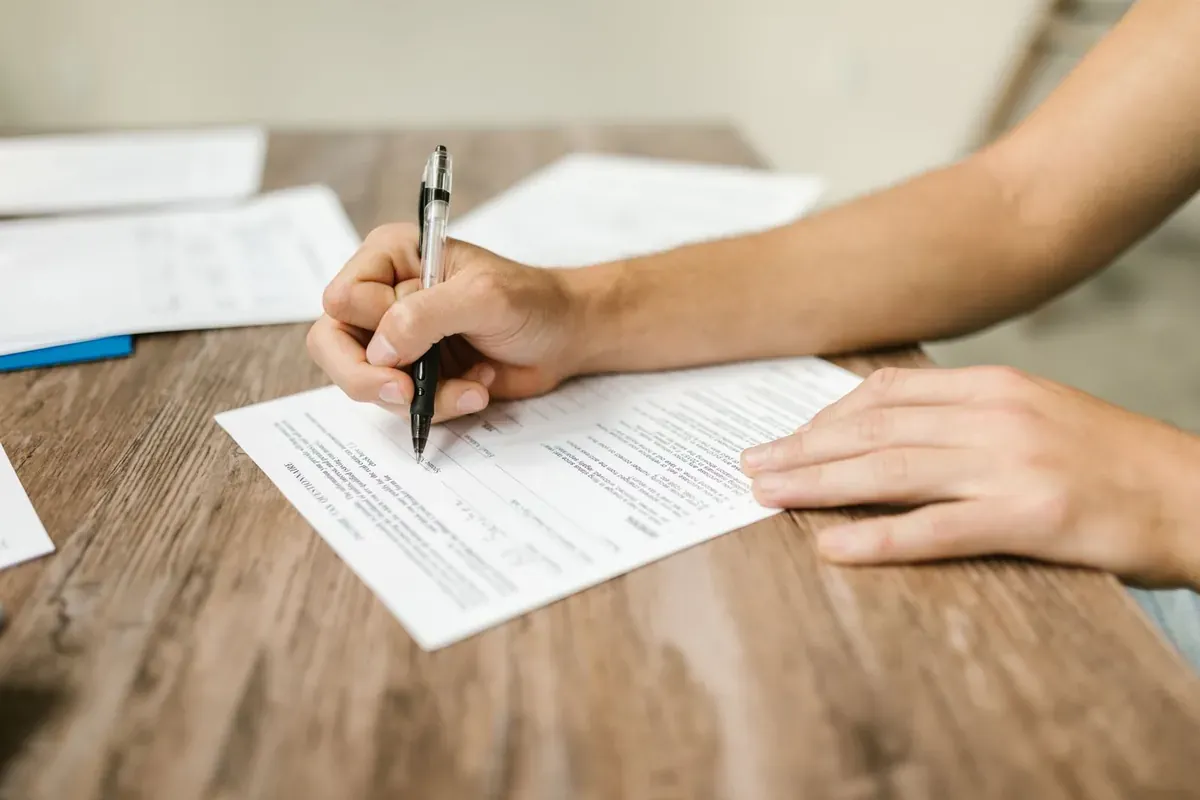 Una persona rellenando un formulario en un escritorio