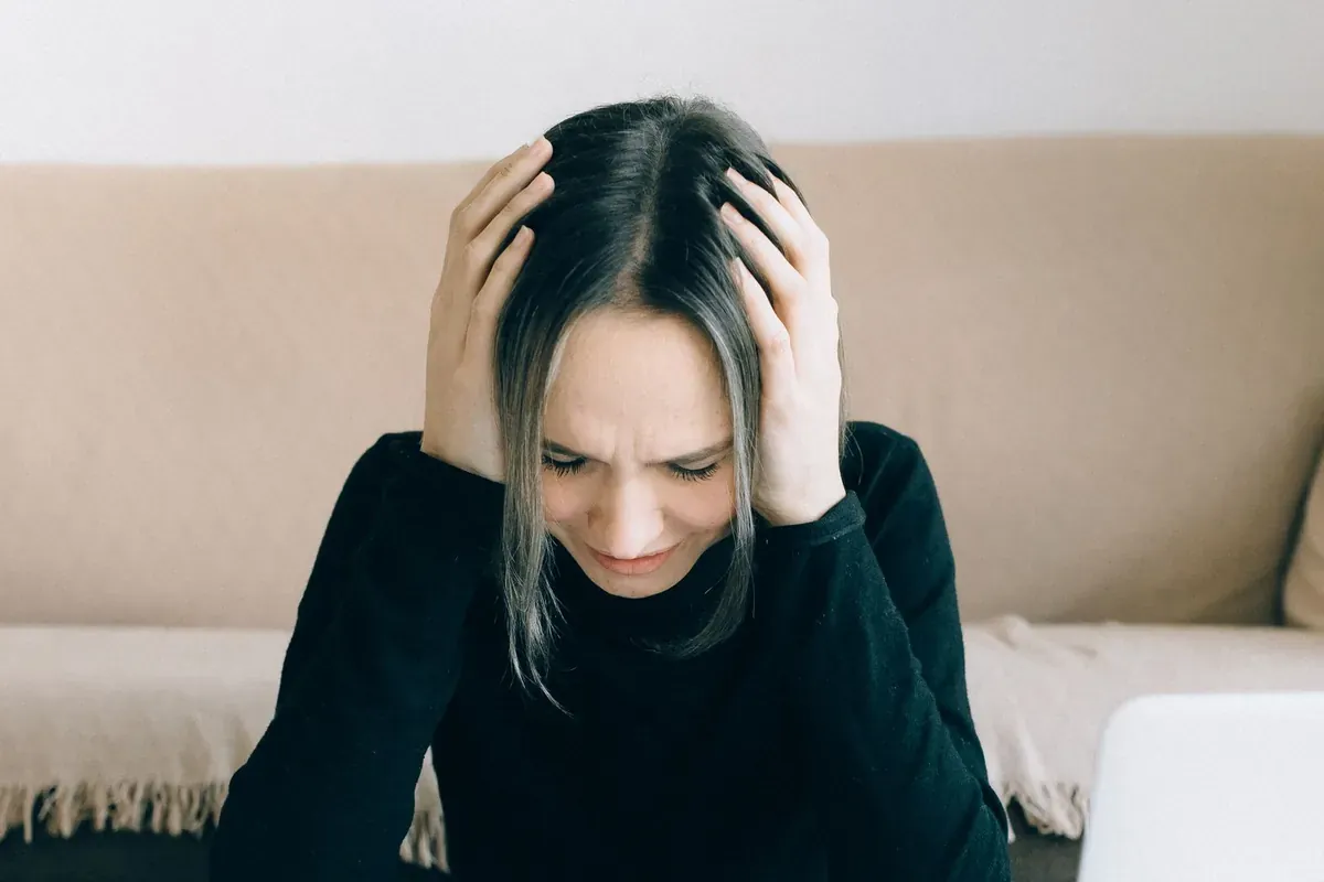 Una persona sentada con la cabeza entre las manos