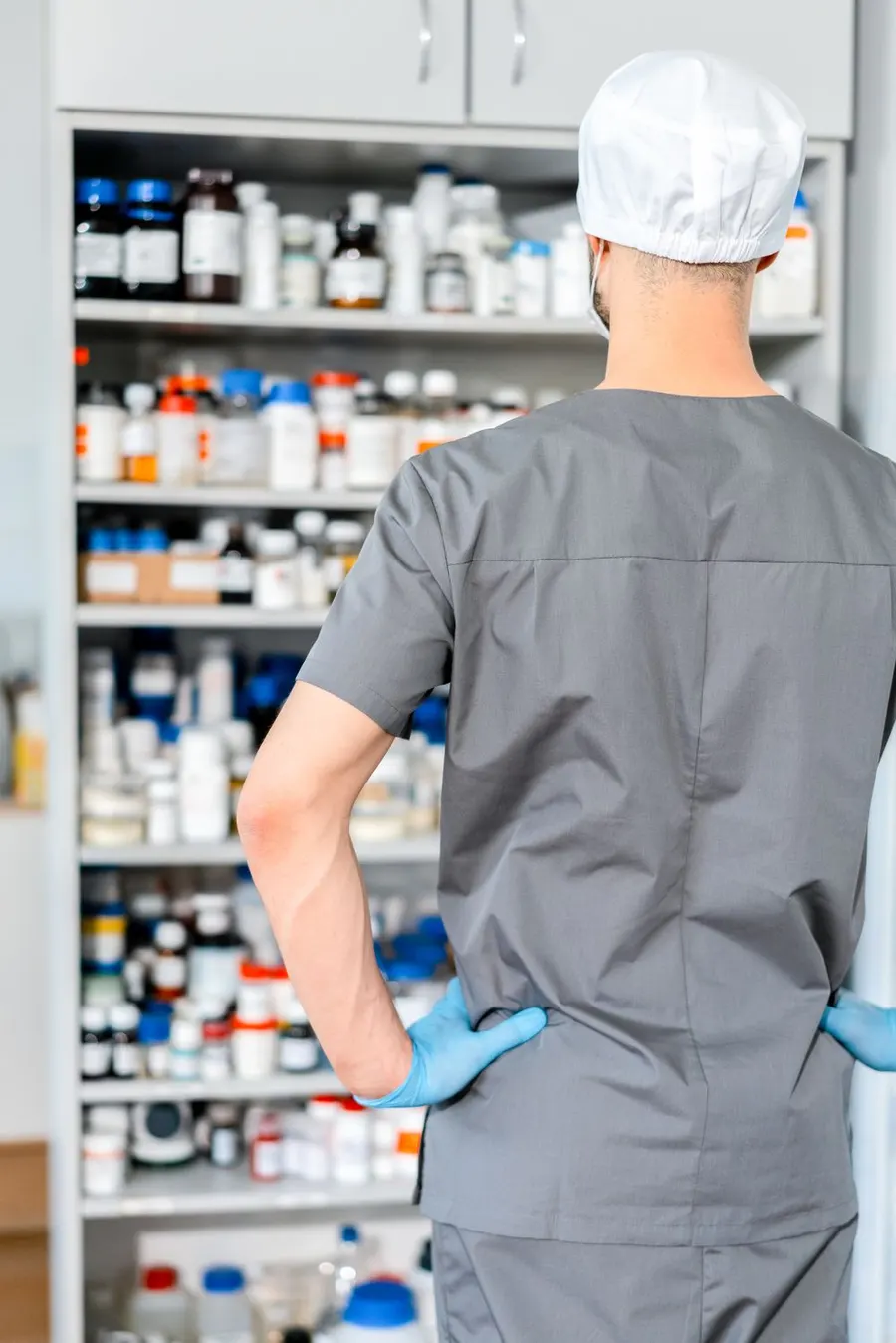 Un farmacéutico prepara medicamentos frente a los estantes
