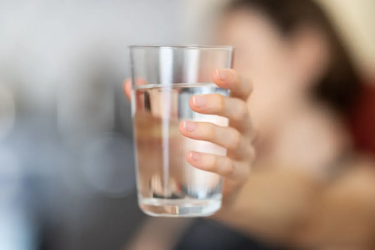 Una mano sosteniendo un vaso de agua
